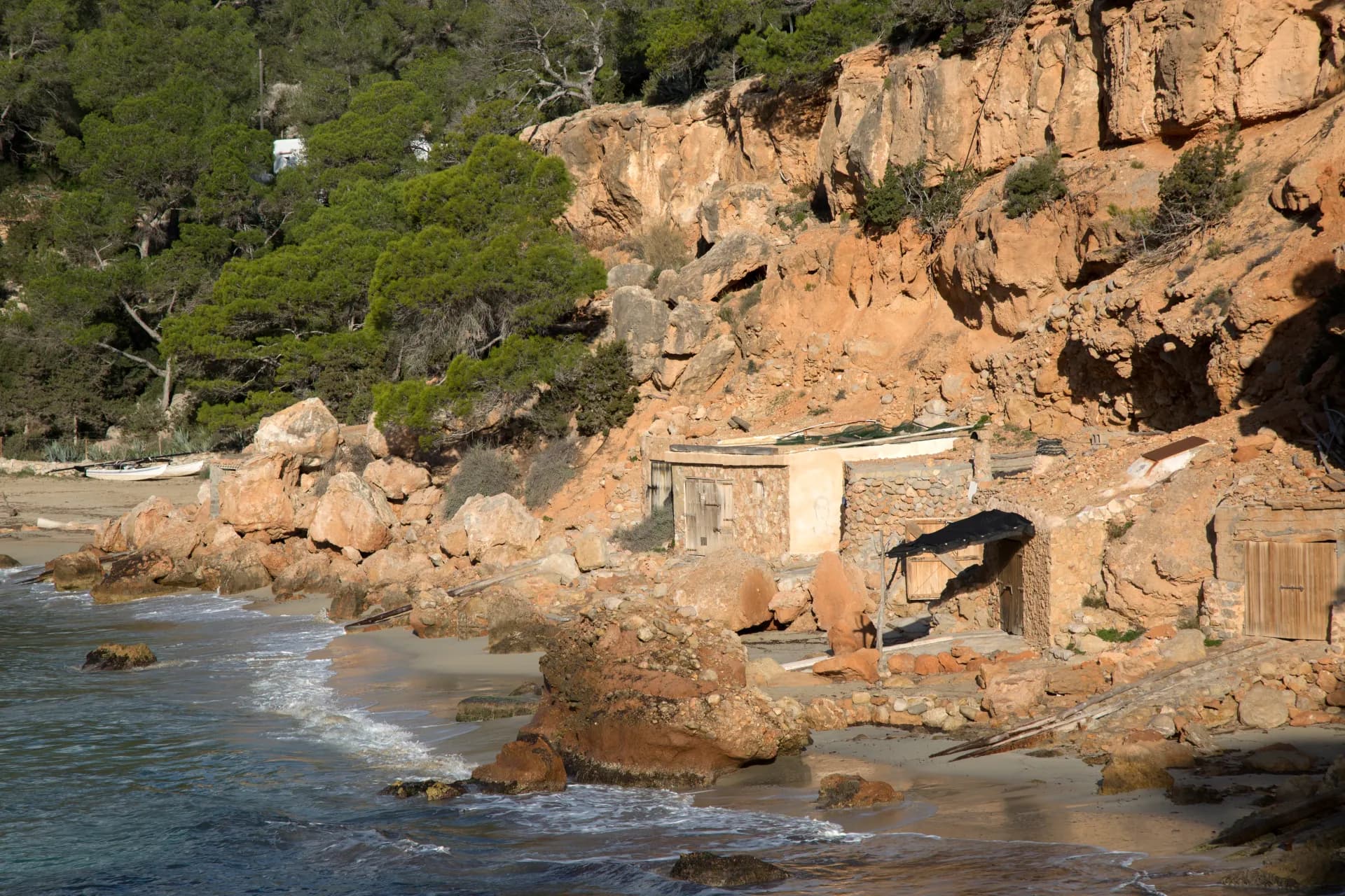 Falaises ocre et cabanes de pêcheurs dans une crique de la côte est de Majorque, la région des grottes du Drach